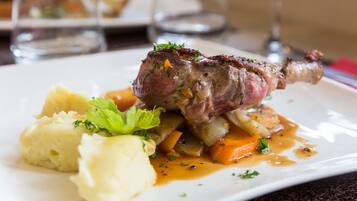 Prato com um bife de cordeiro, purê de batata e legumes assados.