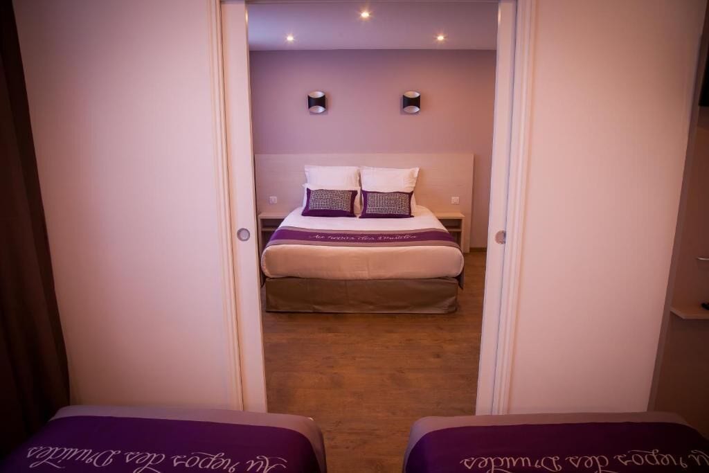 A hotel room with a bed, two bedside tables, and a small seating area with a purple bench.