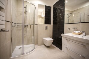A modern bathroom with a glass-enclosed shower, a toilet, and a vanity with drawers and a mirror.
