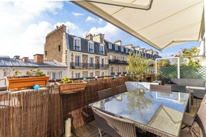 A rooftop terrace with wicker furniture, a glass table, and potted plants. - Chambre d'Amis (Chambres d'Hôtes/BnB/Guest House) (Paris)