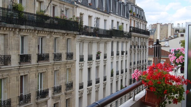 Una hilera de edificios clásicos de estilo europeo, con balcones y persianas uniformes.