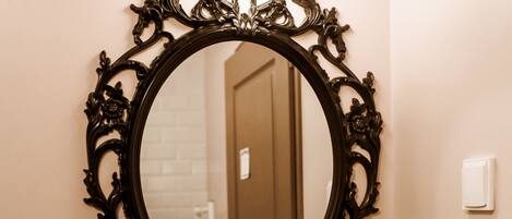 A bathroom with a white sink, ornate black mirror, and white tiled walls.
