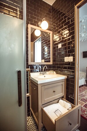 A bathroom with a white sink, a mirror, and a towel drawer.