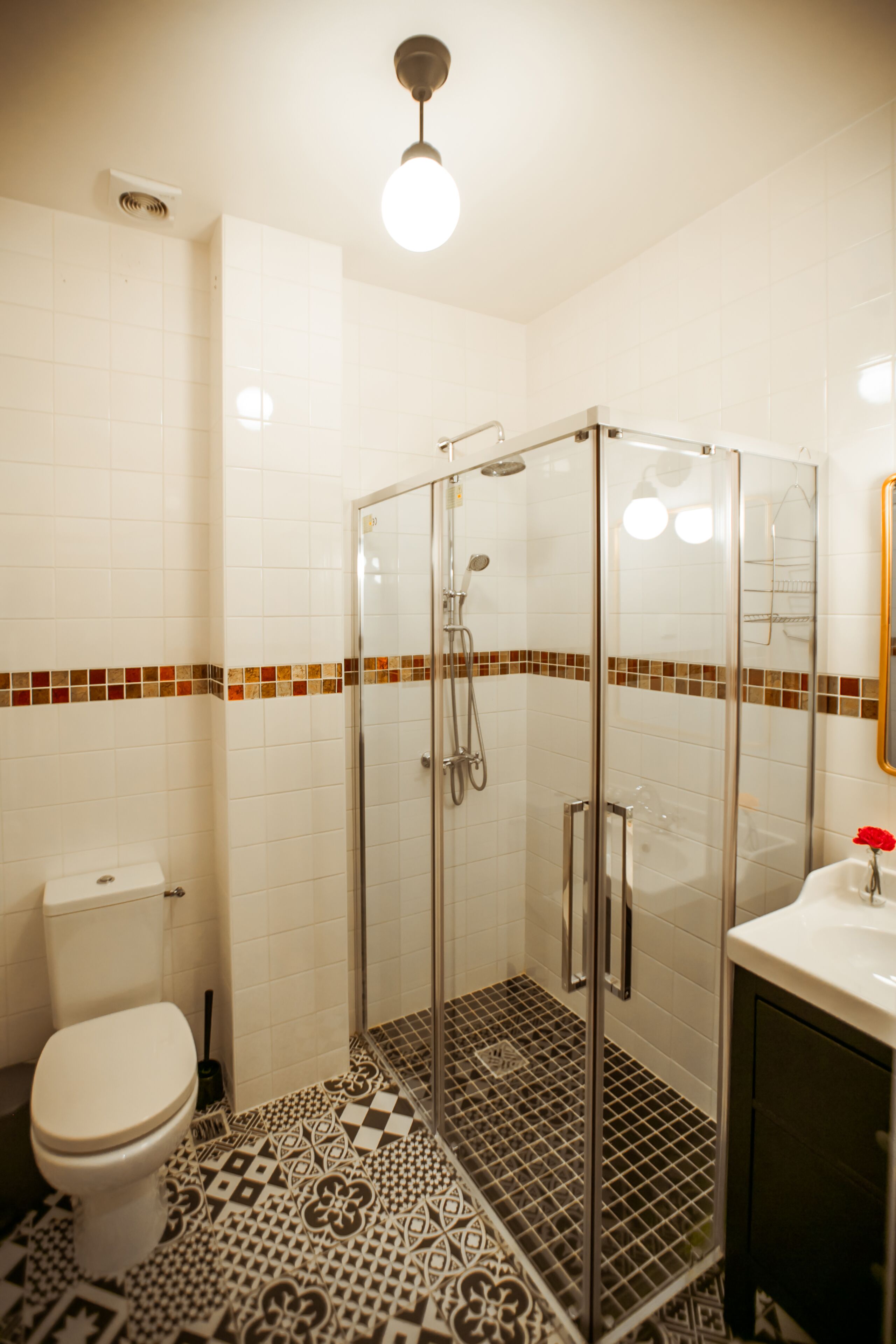 A bathroom with a glass-enclosed shower, a toilet, and a sink.