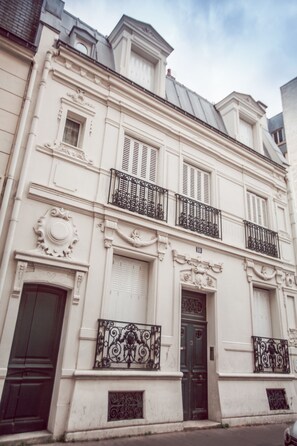 A historic building with ornate architectural details, including decorative moldings, a black iron balcony, and a double door.