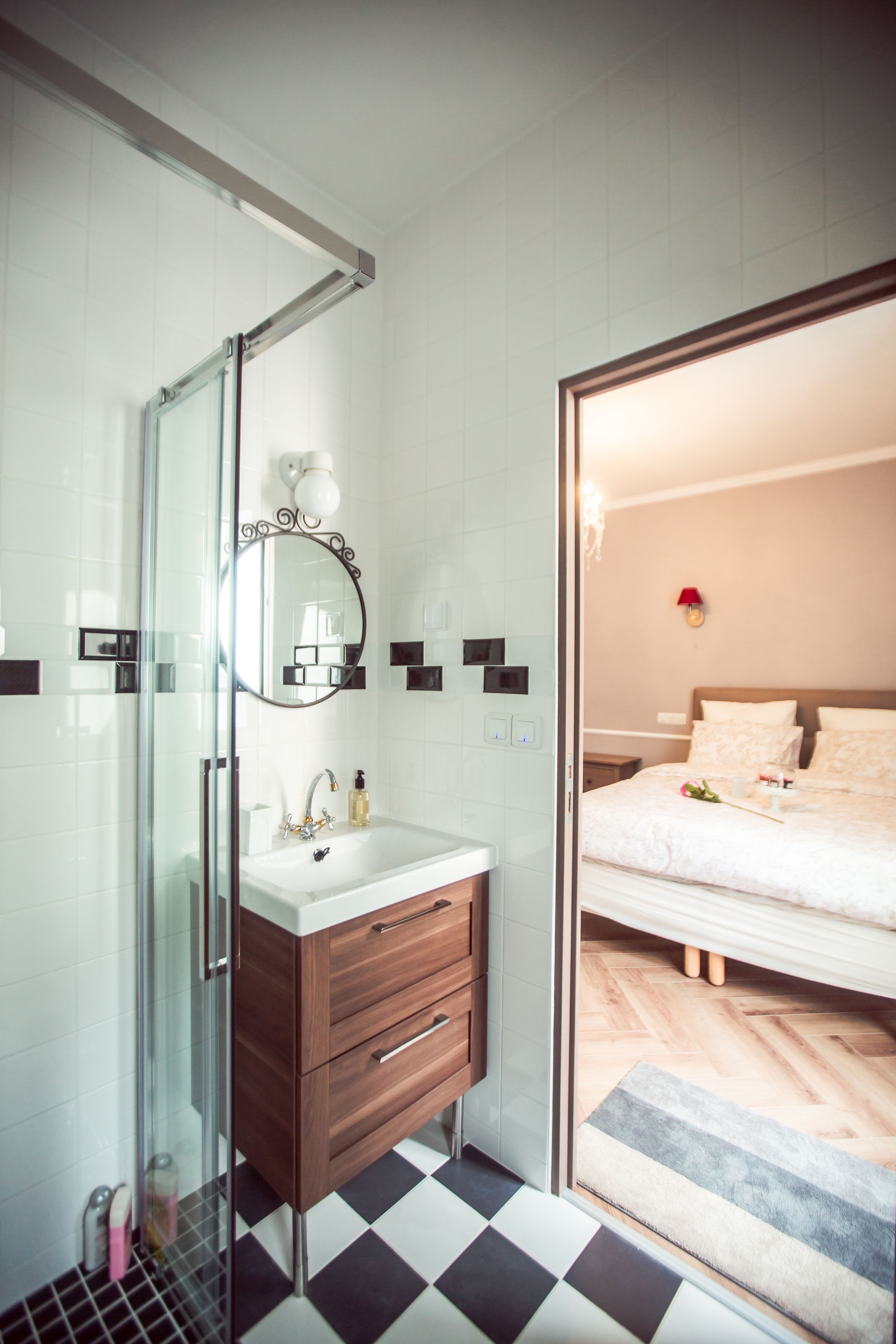 Un baño moderno con cabina de ducha de vidrio, tocador de madera con espejo y piso de cuadros.