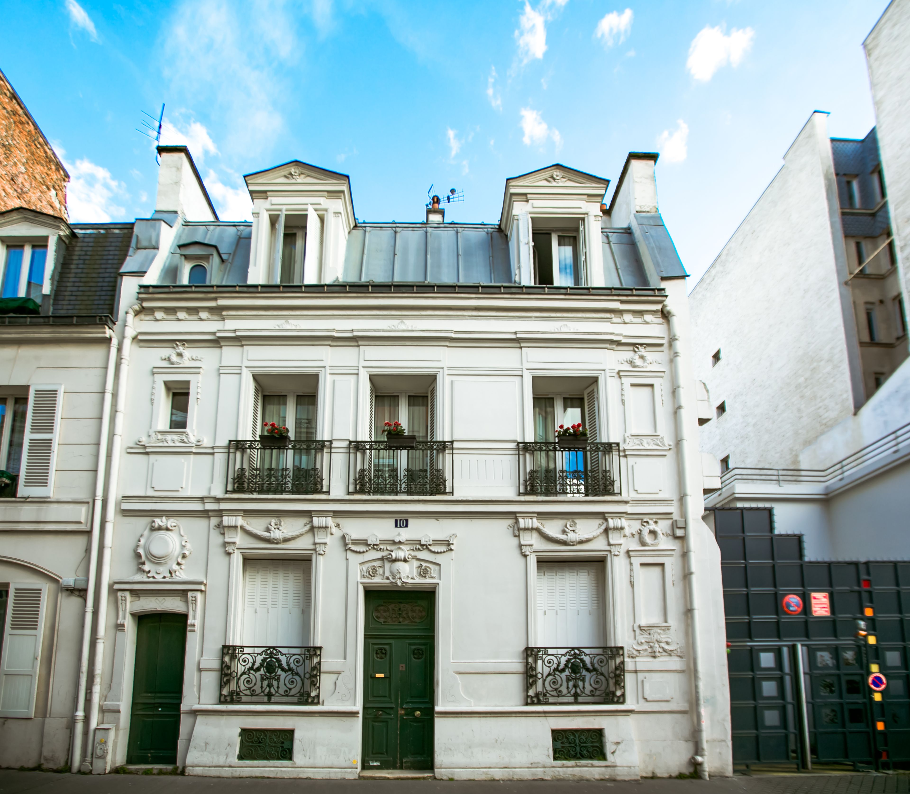 A historic building with a symmetrical facade, two balconies with wrought iron railings, and a green door.