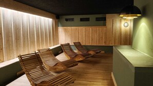 A wooden sauna with benches and a wall-mounted heater. - Hotel Pezzotti (Pellizzano)