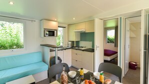 Una habitación compacta con kitchenette, un comedor con mesa para dos, un sofá y una cama.