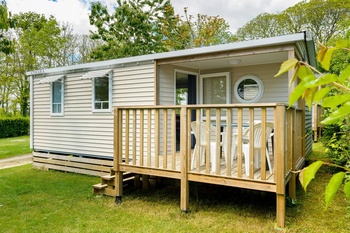 Een stacaravan met terras, een klein portaaltje en een raam.