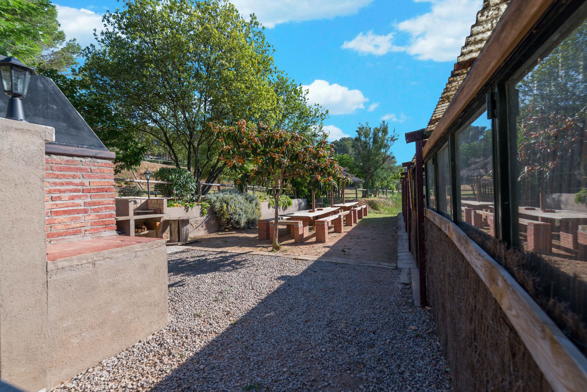 Un patio al aire libre con muros de ladrillo, suelo de grava y bancos de madera.