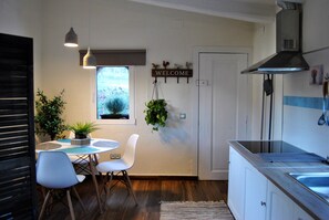 A modern kitchen with a dining area, a welcome sign, and a window with a view. - Comarquinal Bioresort Penedès (Sant Quinti de Mediona)