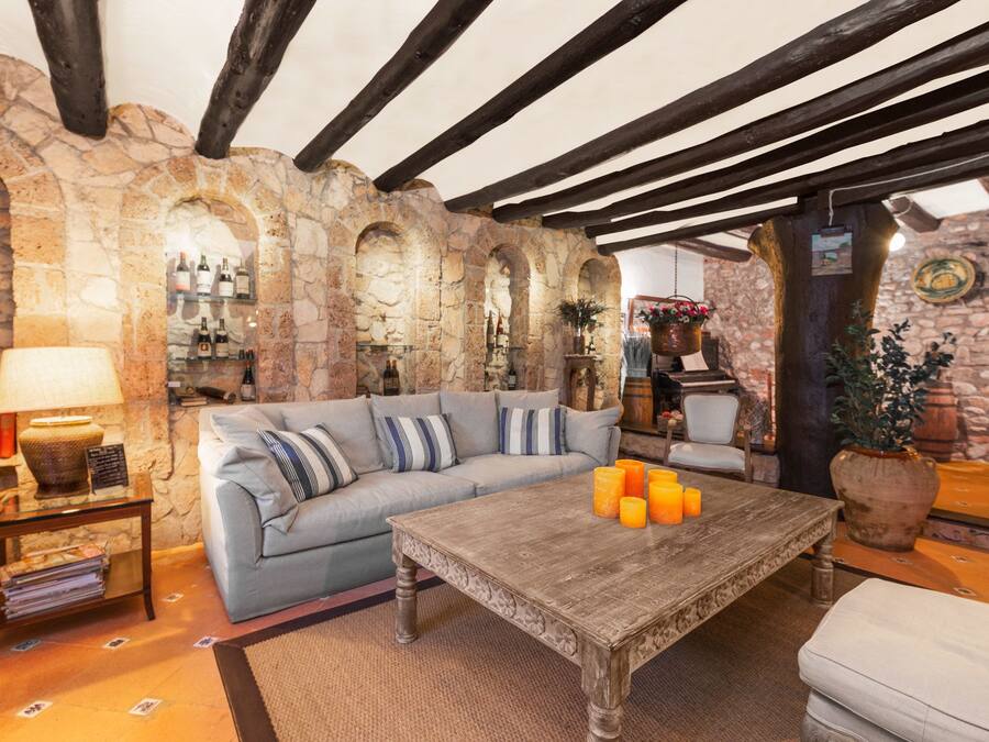 Une pièce chaleureuse avec un mur en pierre, un plafond en bois, un canapé, une table basse et une lampe.