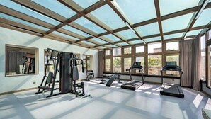 A spacious gym with exercise equipment, large windows, and a high ceiling. - Broma Hotel (Tongchuan)