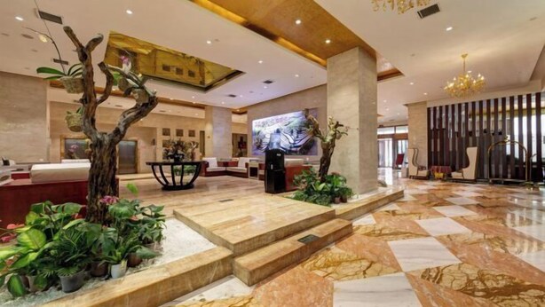 A spacious lobby with a marble floor, a reception desk, a large screen, and a chandelier. - Broma Hotel (Tongchuan)