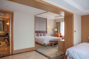 A hotel room with a bed, a desk, a chair, and a bathroom visible through an open door. - Glory Charm Hotel (Fangchenggang)