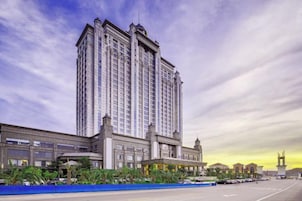 Un hotel moderno de gran altura, con un acceso destacado y un amplio estacionamiento.