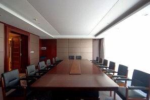 Una sala conferenze con un lungo tavolo e diverse sedie, una porta a sinistra e una finestra a destra.