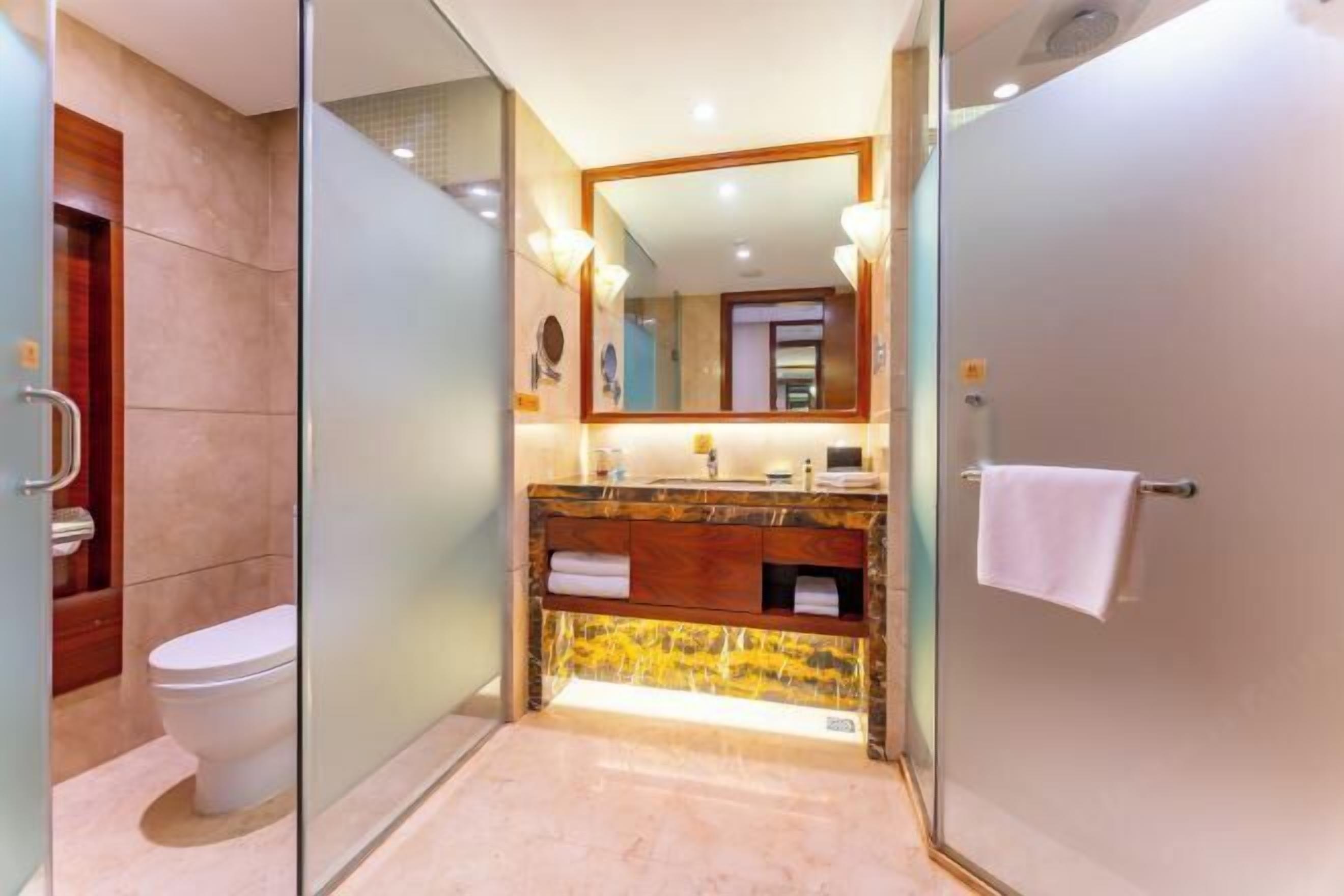 Un baño moderno con cabina de ducha de vidrio, inodoro blanco y tocador con encimera de mármol.