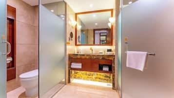 Een moderne badkamer met een douchecabine van glas, een wit toilet en een wastafel met een marmeren aanrecht.