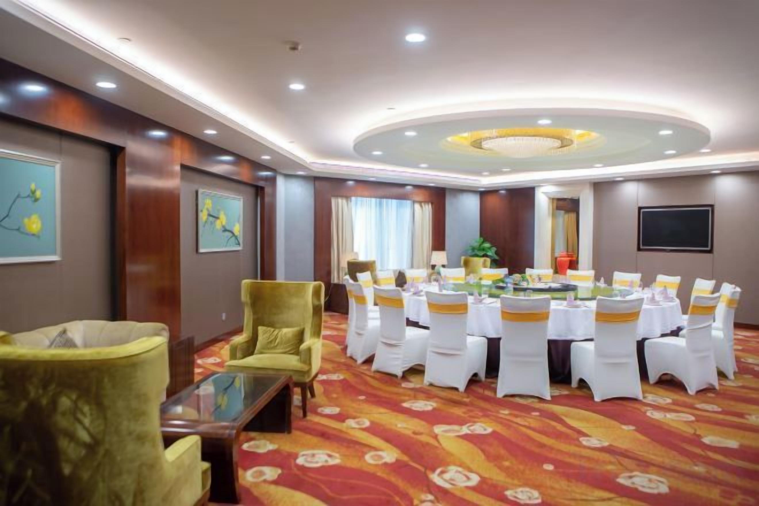 A conference room with a round table, white chairs, and a carpeted floor.