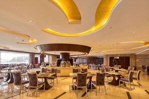 Un'ampia hall d'albergo con un'area bar centrale, diverse opzioni di seduta e un design moderno del soffitto.