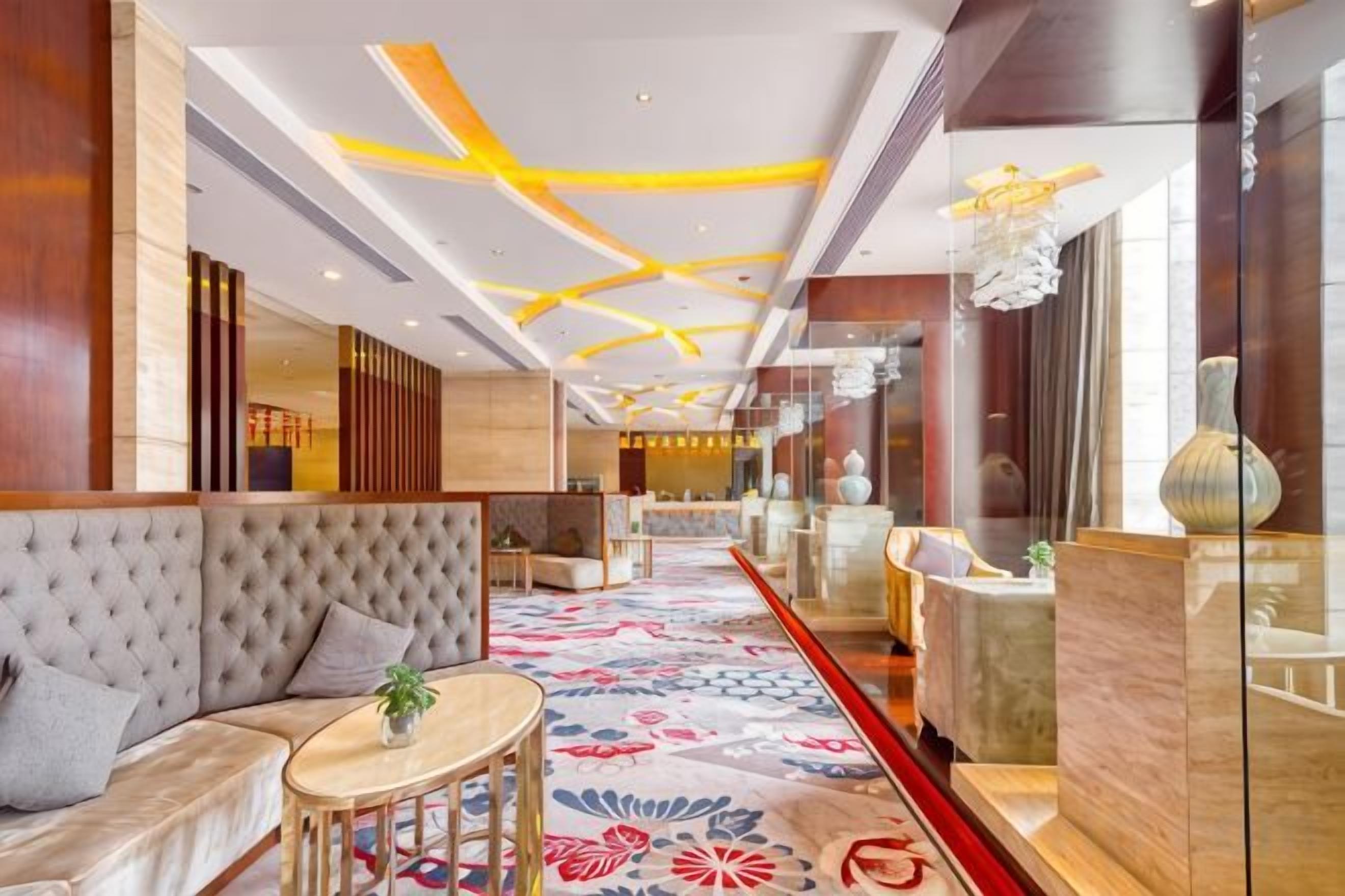 A hotel lobby with a sofa, a small round table, and a decorative vase.