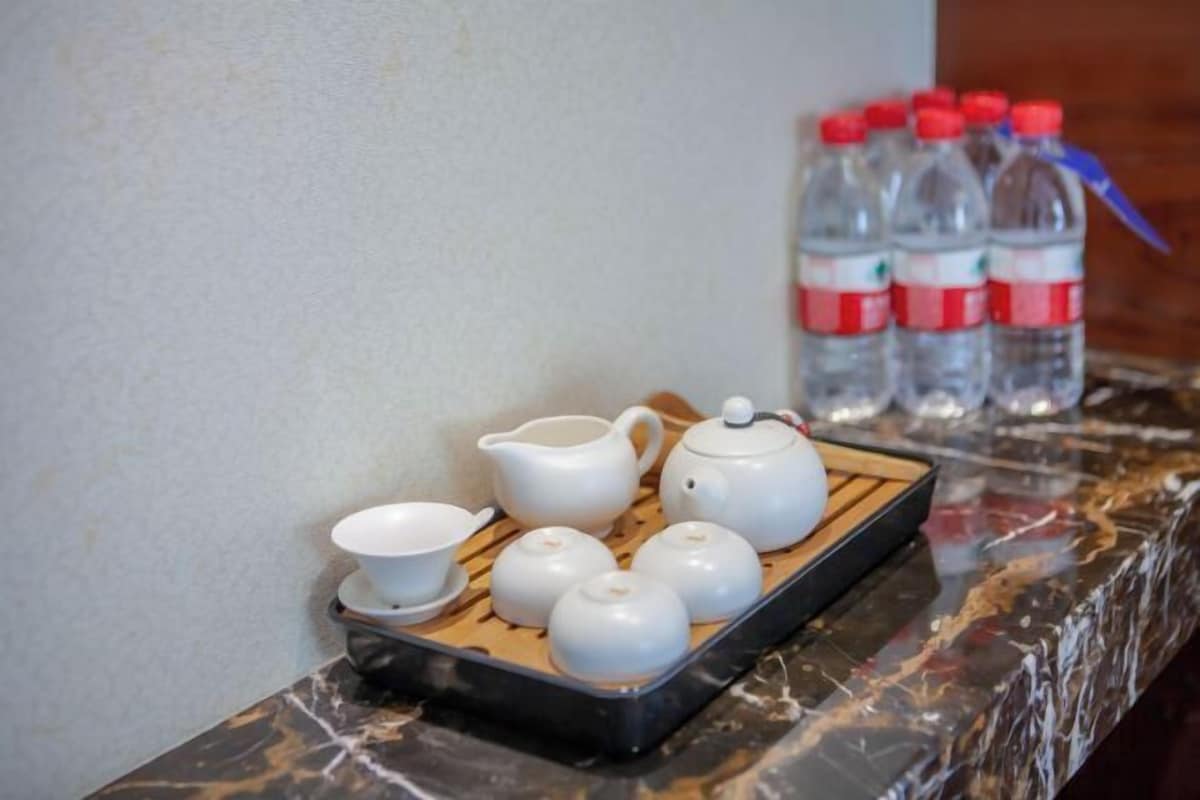A tray with teapots and cups on a marble countertop, with water bottles in the background.