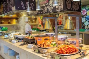 A buffet with various food items and a chef in the background.