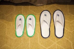 Une paire de chaussons verts et blancs ornés d’un logo, et deux paires de chaussons blancs unis, également ornés d’un logo sur une surface texturée.