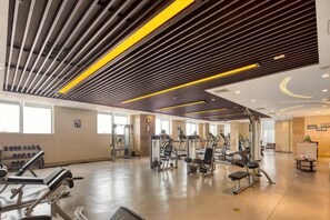 Een sportschool met trainingsapparatuur, grote ramen en een modern plafondontwerp.