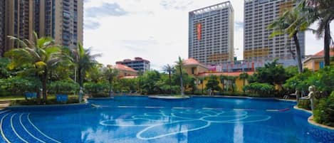 A swimming pool surrounded by greenery and tall buildings.