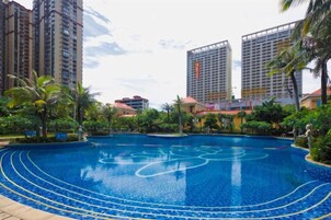 Una piscina rodeada de follaje y edificios altos.