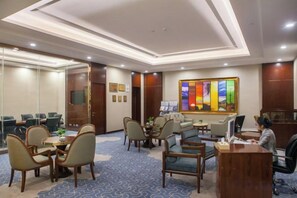 Una sala conferenze di un hotel con un grande quadro, una reception e diverse zone salotto.