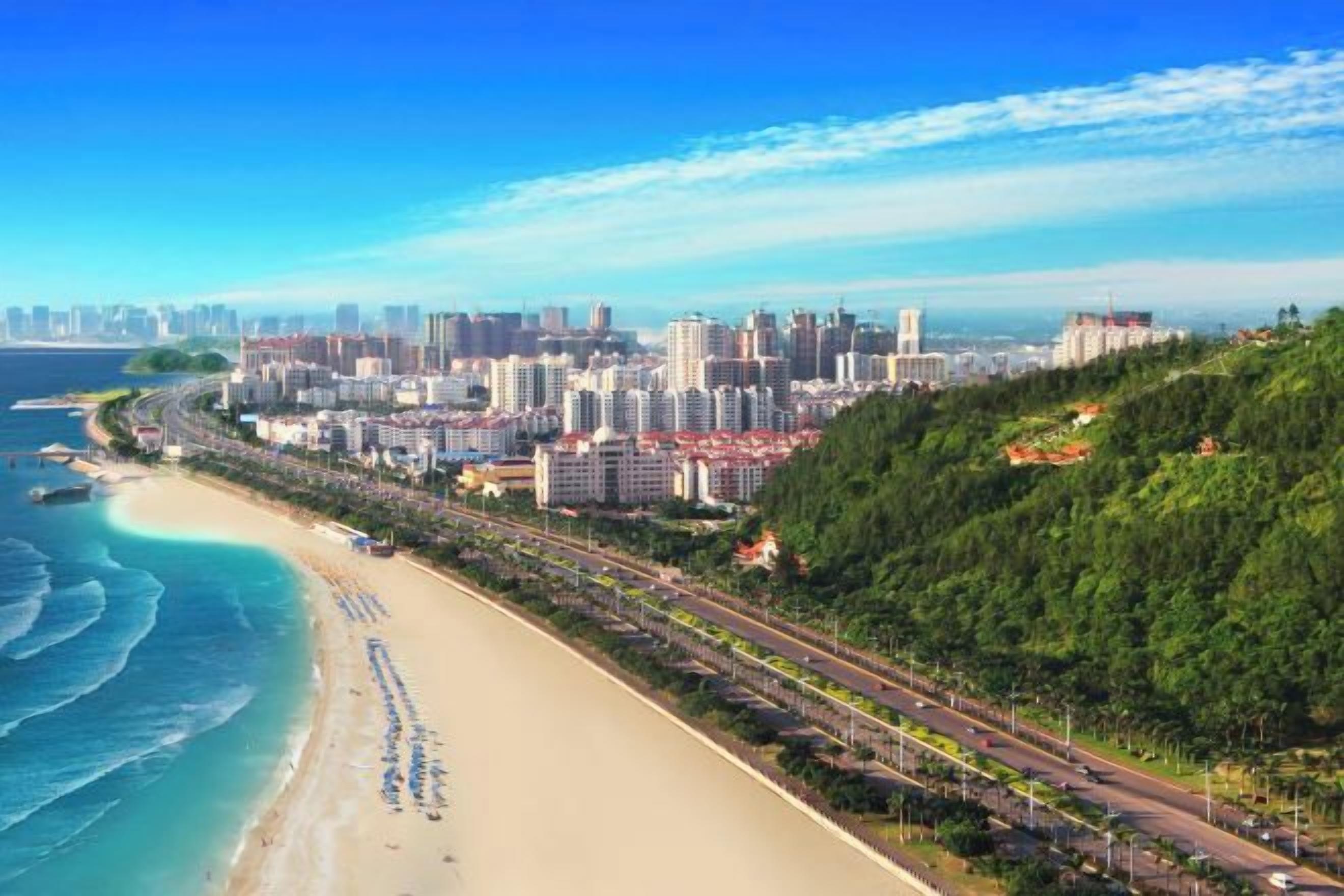 A coastal cityscape with a beach, high-rise buildings, and a road running parallel to the shore.