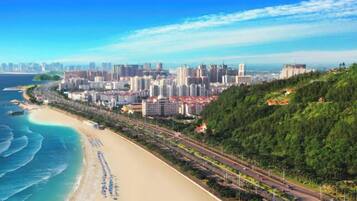 A coastal cityscape with a beach, high-rise buildings, and a road running parallel to the shore.