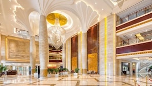 Eine geräumige Lobby mit hohen Decken, einer zentralen Säule und einem Chandelier.