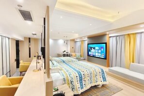 A modern hotel room with a bed, a TV, a sofa, and a desk. - Huidong Hotel (Zigong City)