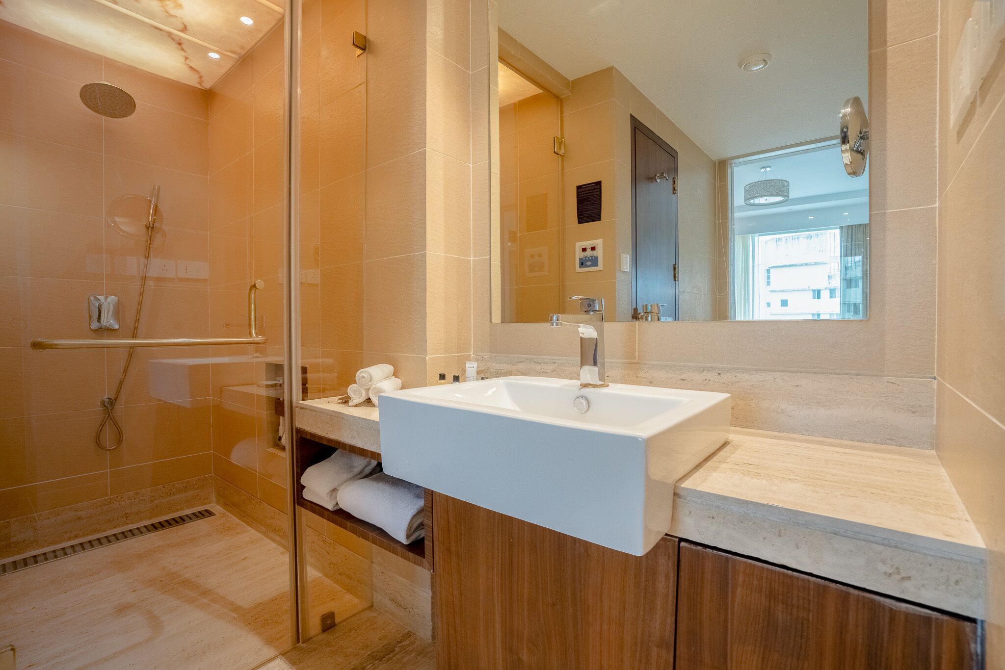 Un baño moderno con cabina de ducha de vidrio, un lavabo blanco y un espejo grande.
