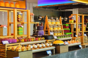 Una vitrina de panadería con diversos productos horneados y frascos de conservas.