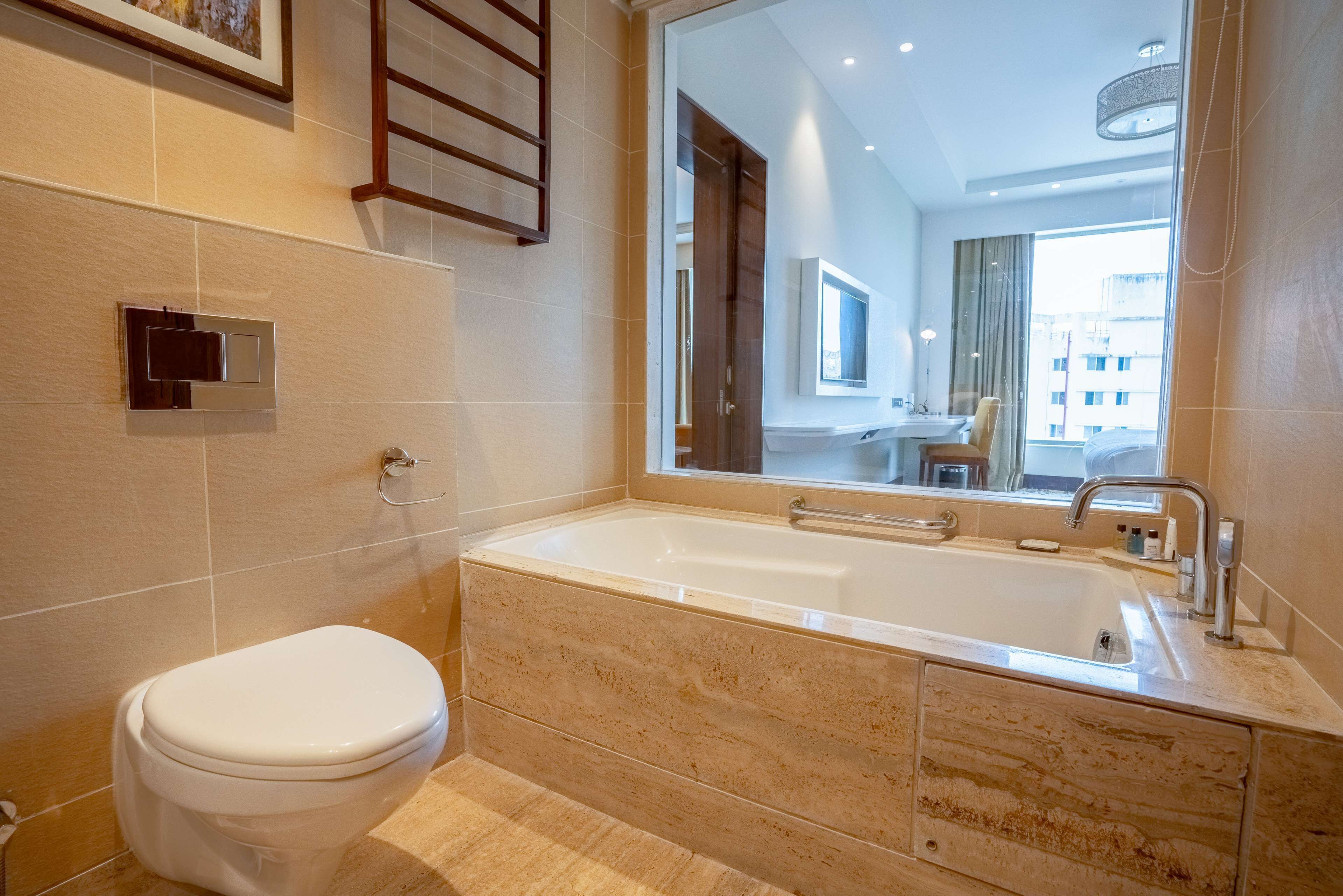 Un baño moderno con una bañera grande, un inodoro y un espejo.