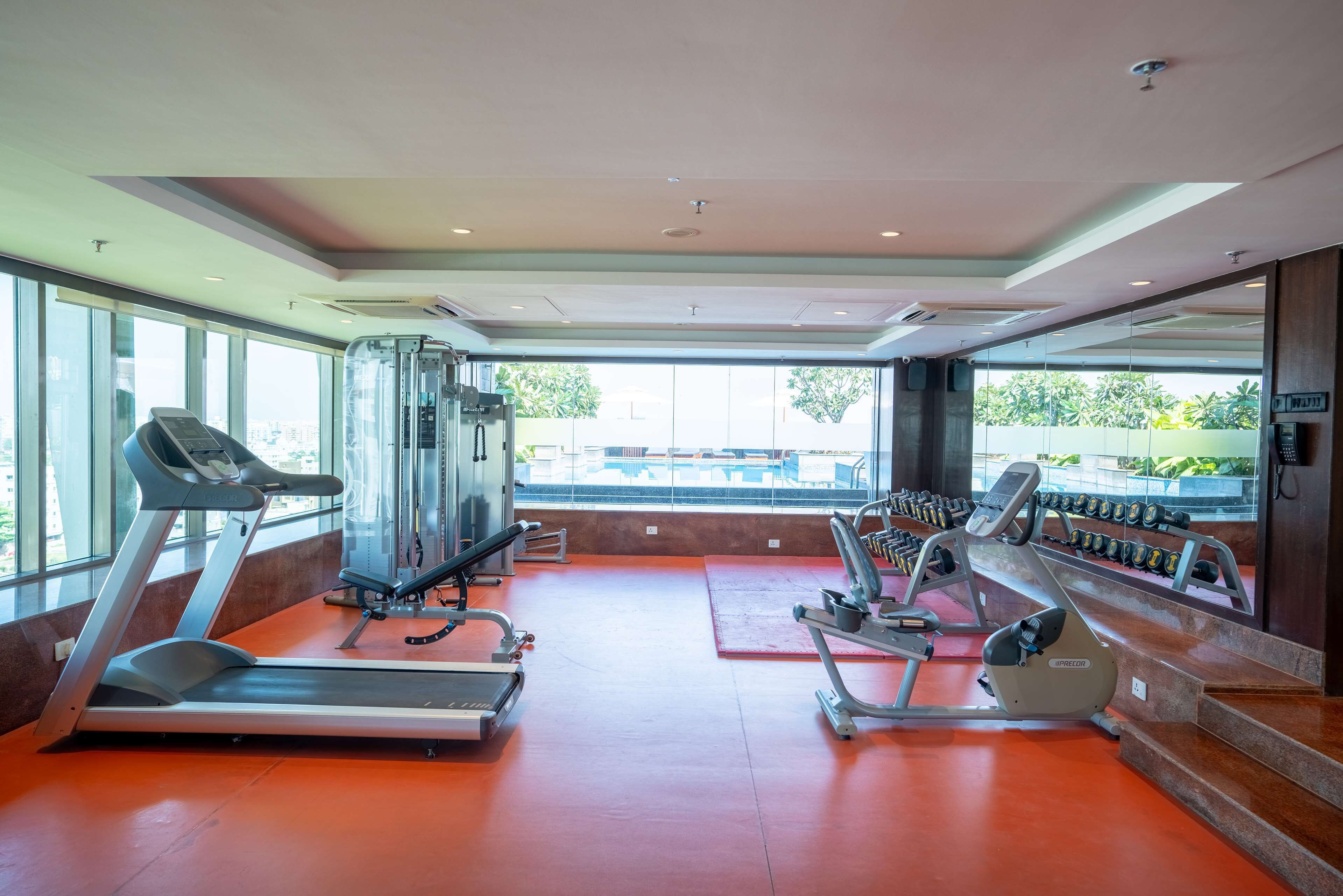A gym with treadmills, weight machines, and a mirrored wall.