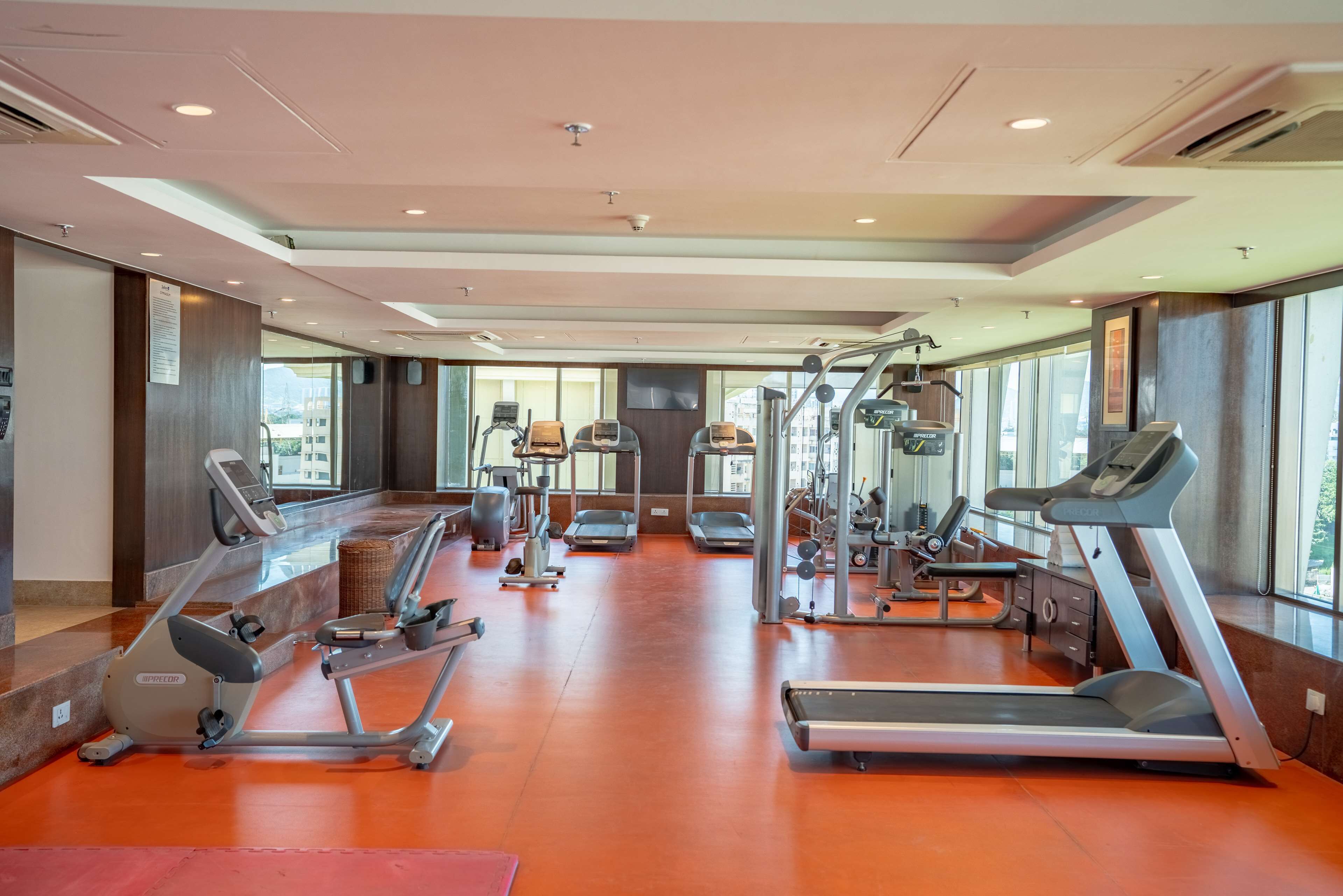 Ein Fitnessstudio mit Laufbändern, Crosstrainern und Gewichtecken.