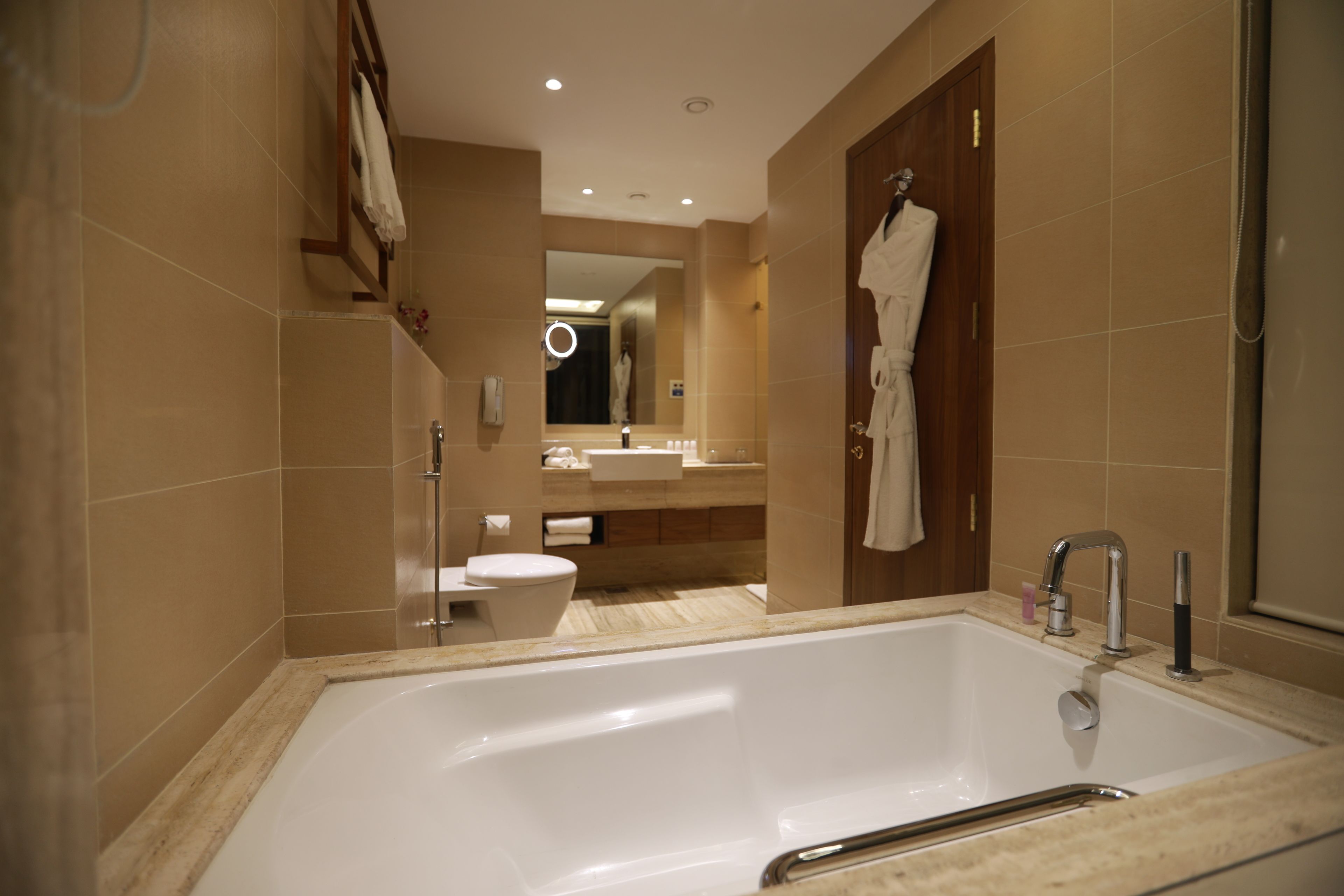 A modern bathroom with a large bathtub, a toilet, and a vanity with a mirror.