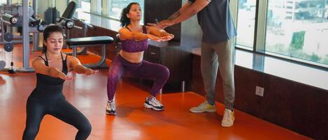 Une salle de sport équipée de matériel d’exercice et dotée de grandes fenêtres.