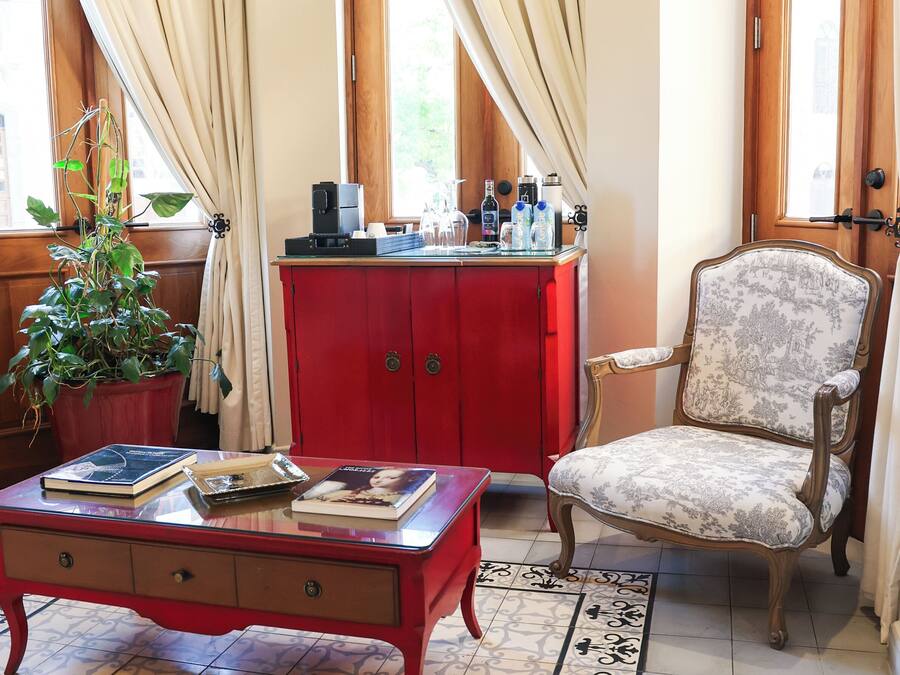 Ein Zimmer mit einem roten Schrank, einem gemusterten Teppich, einem Stuhl und einer Topfpflanze.