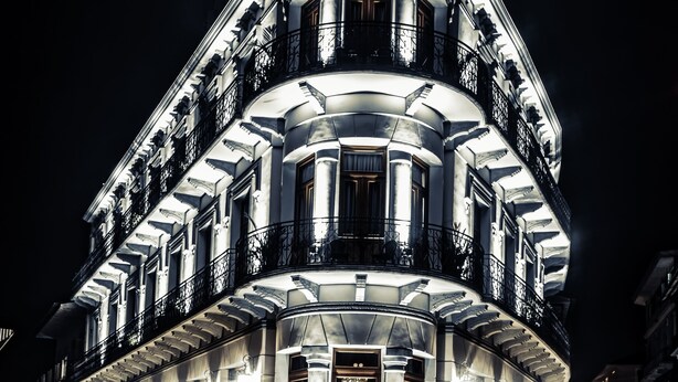 Un edificio imponente e iluminado con fachada simétrica, varios balcones y una entrada destacada.
