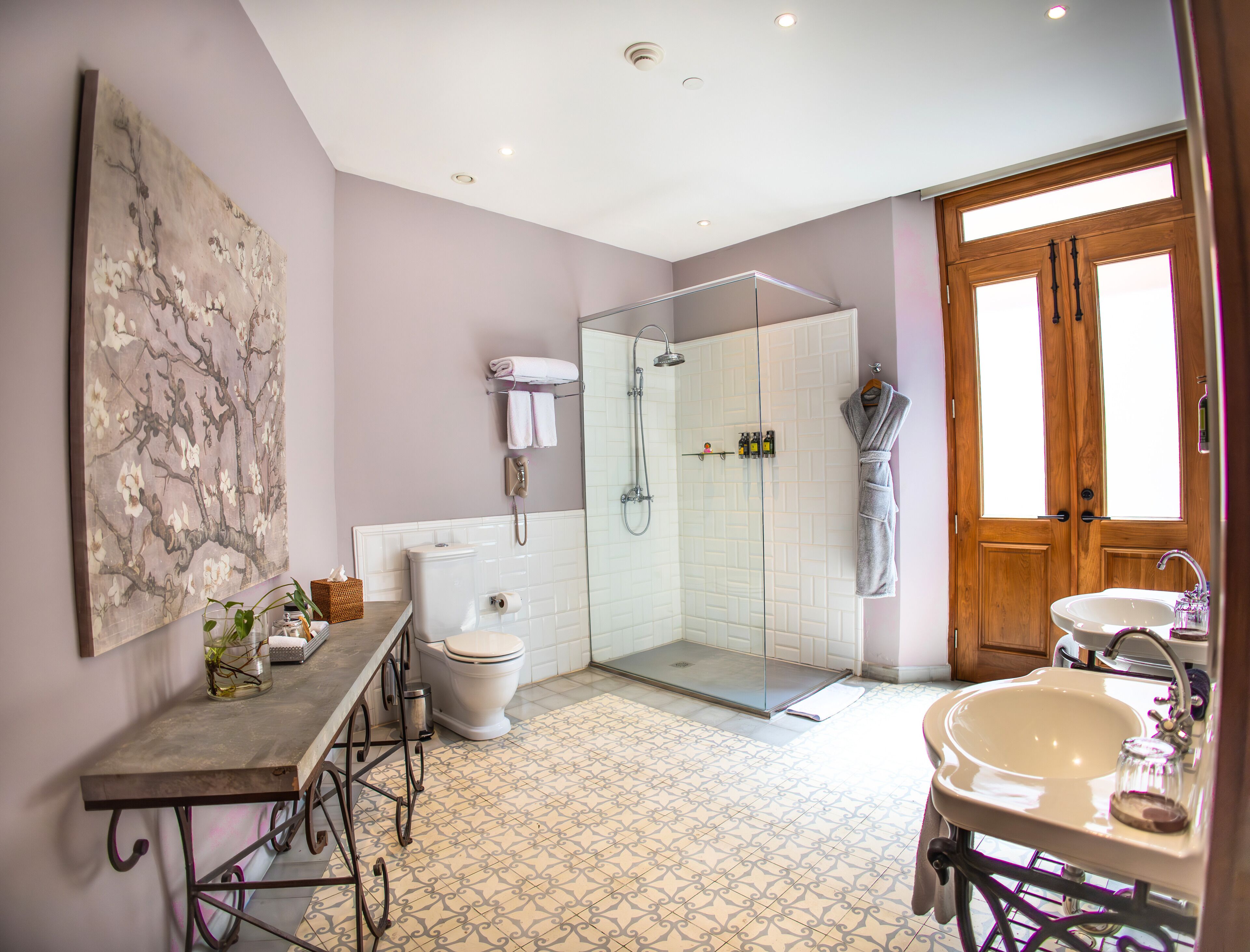 A bathroom with a toilet, shower, sink, and a large window.