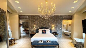 Un dormitorio espacioso con una cama grande, un candelabro, un baño con bañera y un comedor.