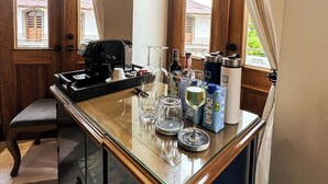 Una cocina con una mesa de vidrio, una cafetera, copas de vino y una botella de vino.